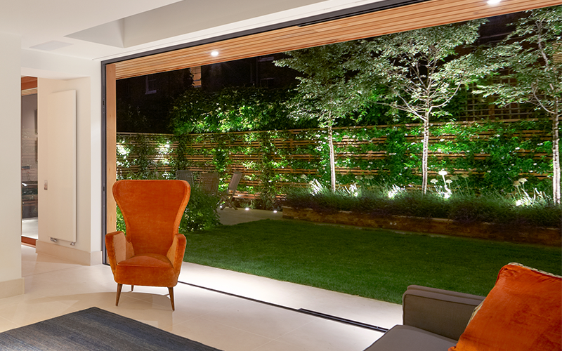 Living area looking out onto lit small garden