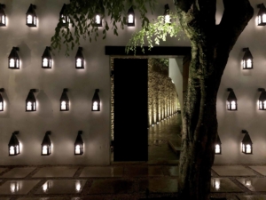 Lanterns lit on wall with uplighters in the distance as part of a courtyard scheme 