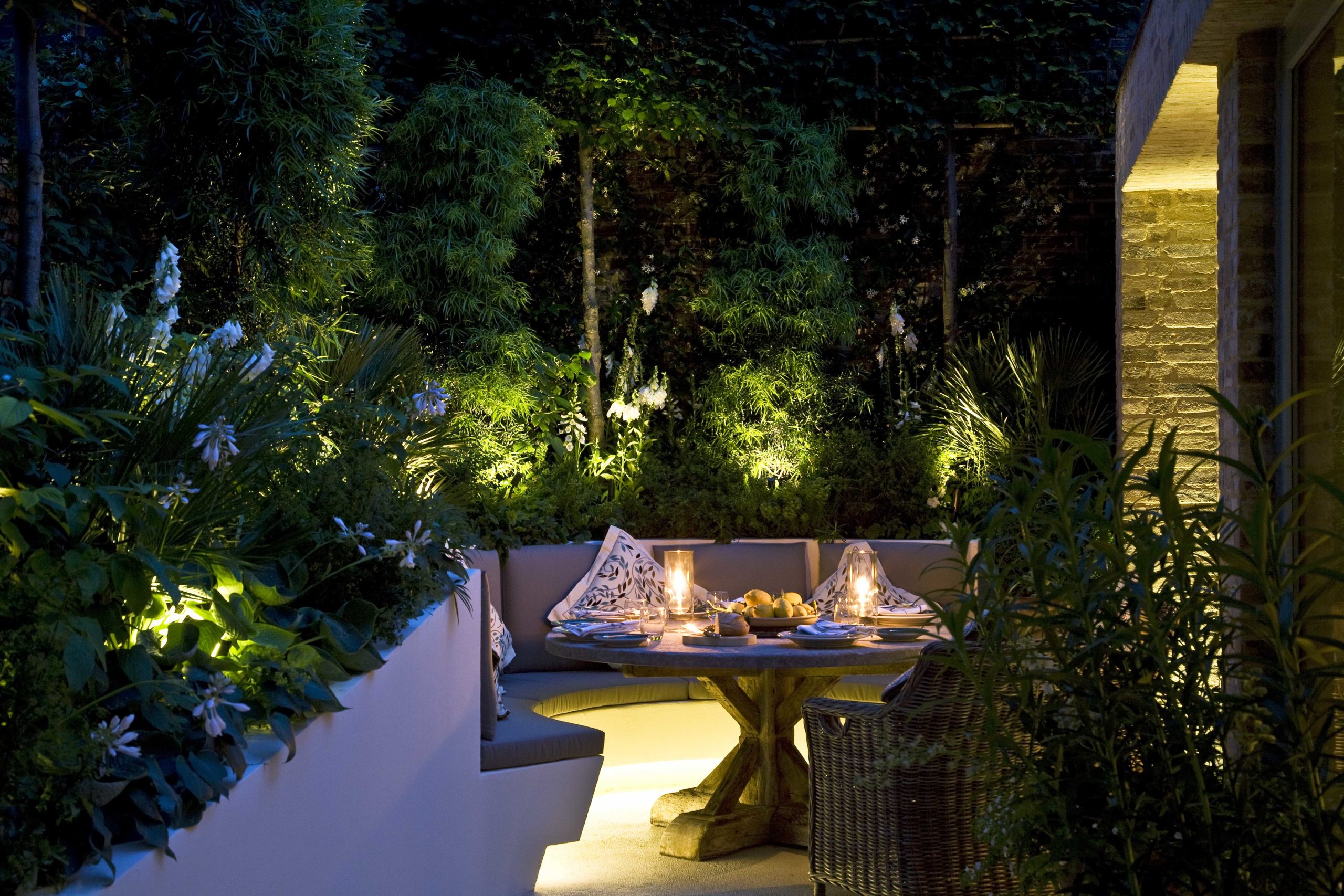 Outdoor seating area lit with linear strip under seating and spike lights in planting