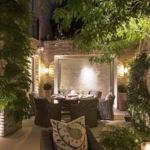 Outdoor dining area lit with wall lights and lucca uplights