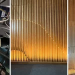 Office atrium with long circular pendant and uplit slated wooden wall