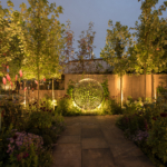garden lighting ideas of a path to back lit sculpture with planting lit each side