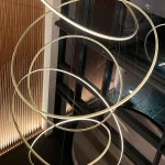 circular pendant fills triple height atrium with uplit wooden wall