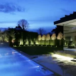 uplit garden surrounding outdoor swimming pool