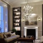 view to lit shelving either side of uplit fireplace with chandelier