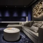Dark blue media room with sofa, wall art lit from behind and downlights to walls