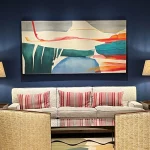 dark blue wall with red table lamps framing colourful art beautifully lit