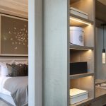 Bedroom with divider wall dresser area with lit shelves
