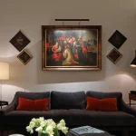 Sofa with painting above lit with picture light and table lamps either side