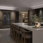 Kitchen island with downlights onto counter top and fridge with wine at far end
