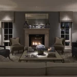 Living room with sofas arounda fireplace and coffee table with flowers lit from downlight above