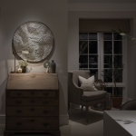 textured artwork lit with downlight above desk