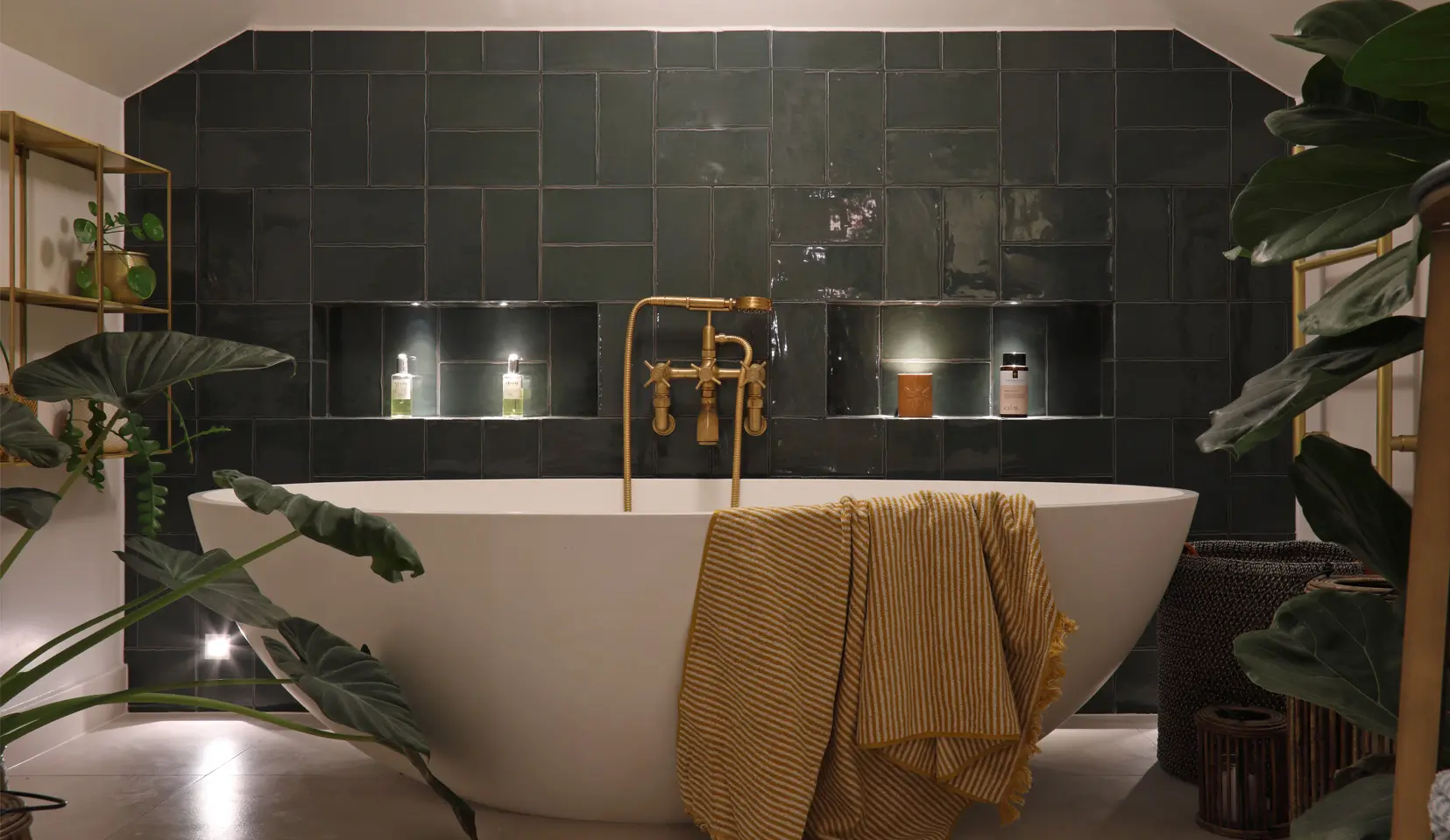 Bath with green tiled backdrop and low level lighting