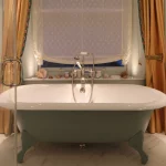 Roll top bath in traditional bathroom with uplights to window reveals