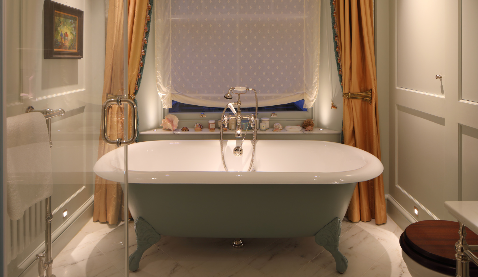 Roll top bath in traditional bathroom with uplights to window reveals