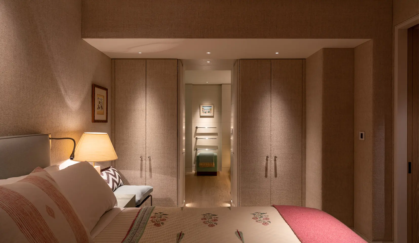 Bedroom with built in wardrobes and art lit beyond