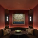 Red walled booth seating area with picture light above painting