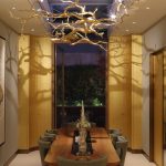 View into dining room with gold hanging tree sculpture above table with spotlights lighting from above