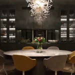 Dining room with glass shelving units with integrated lighting in background