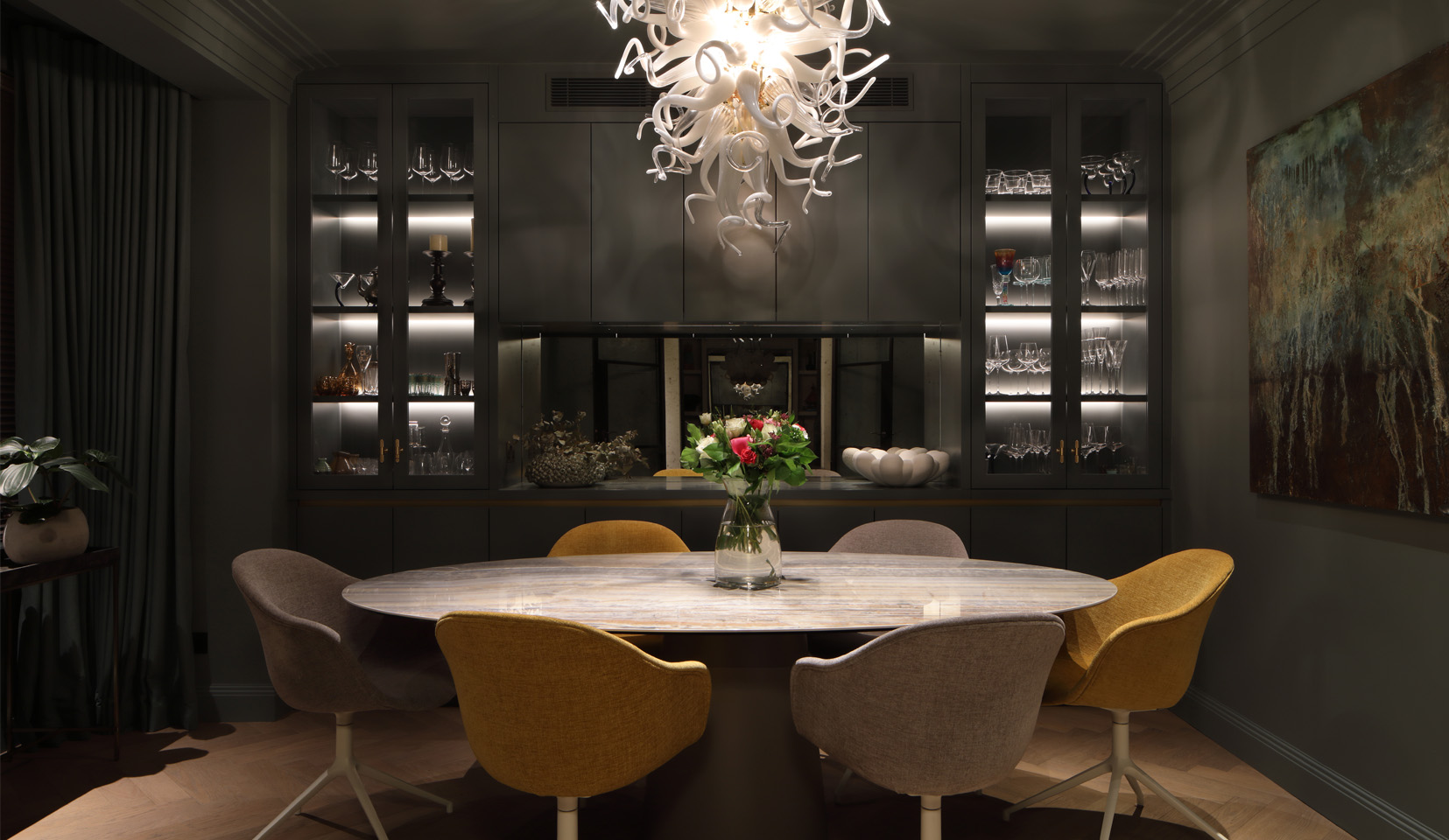 Dining room with glass shelving units with integrated lighting in background