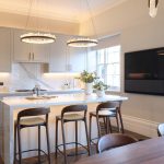 Kitchen island with pendants above and countertops lit with linear light beyond