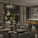 Kitchen with dining table and lit from downlights and pendant above, with open doors out onto garden