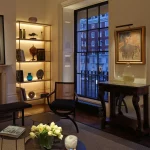 Living room with lit shelving unit and flowers lit with pinspot downlight on coffee table