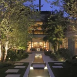 View of garden through to house with lit water feature and planting