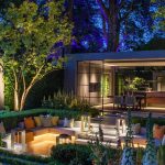 wonderfully planting surrounds a lit sunken garden area with a kitchen in the background