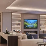 luxury living room with lit coffered ceiling and shelving units