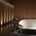 atmospheric corridor with uplit textured wall and white seating