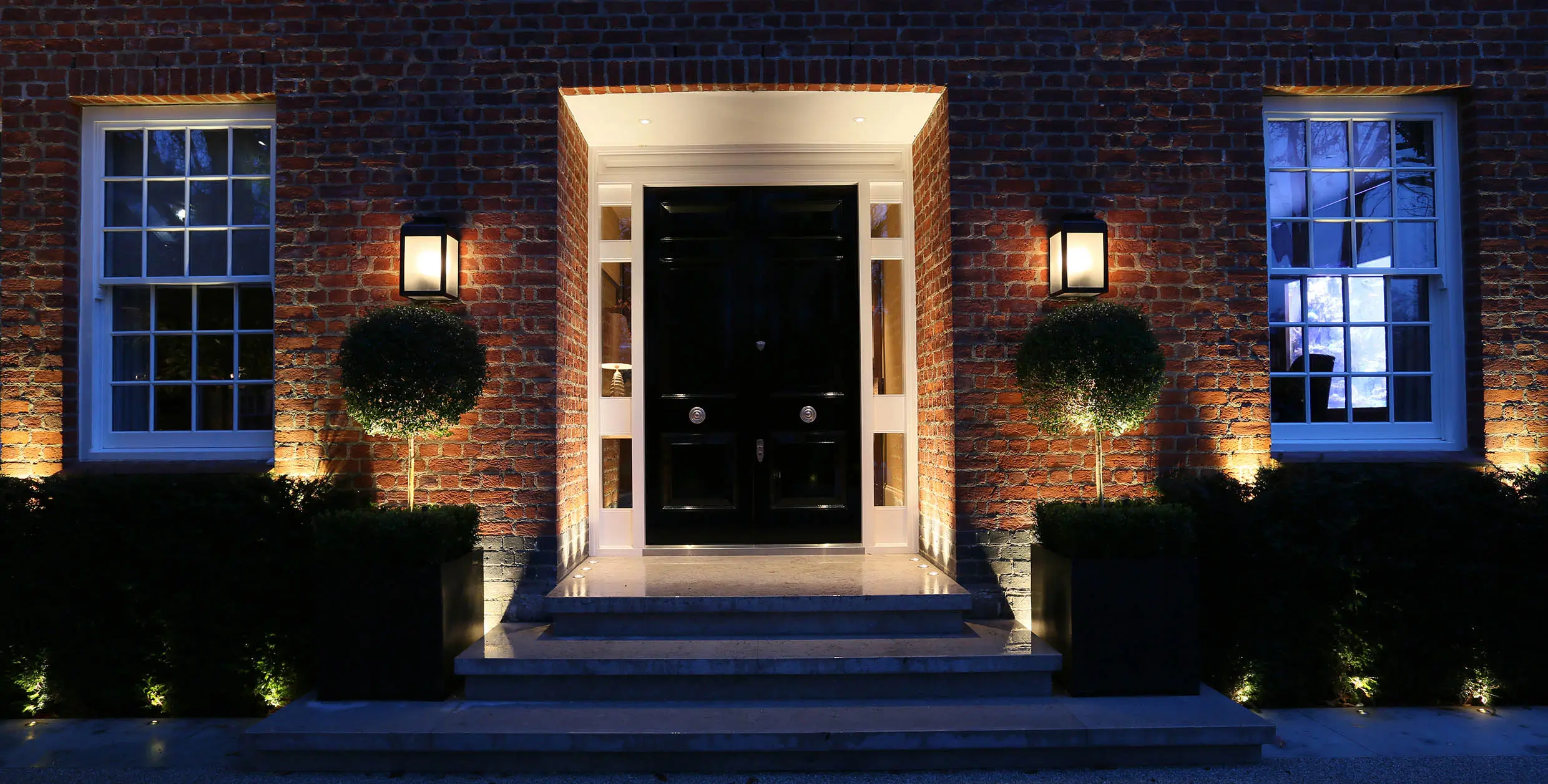 clever symetrical front door lighting with a combination of lanterns and uplights