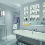white bathroom with shelving above bath and low level lighting