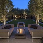 Patio garden with seating surrounded by uplit multi-stemmed trees