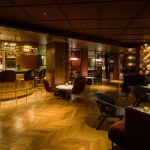 Marylebone Hotel Bar with bar stools and small tables with pinpoint spotlights