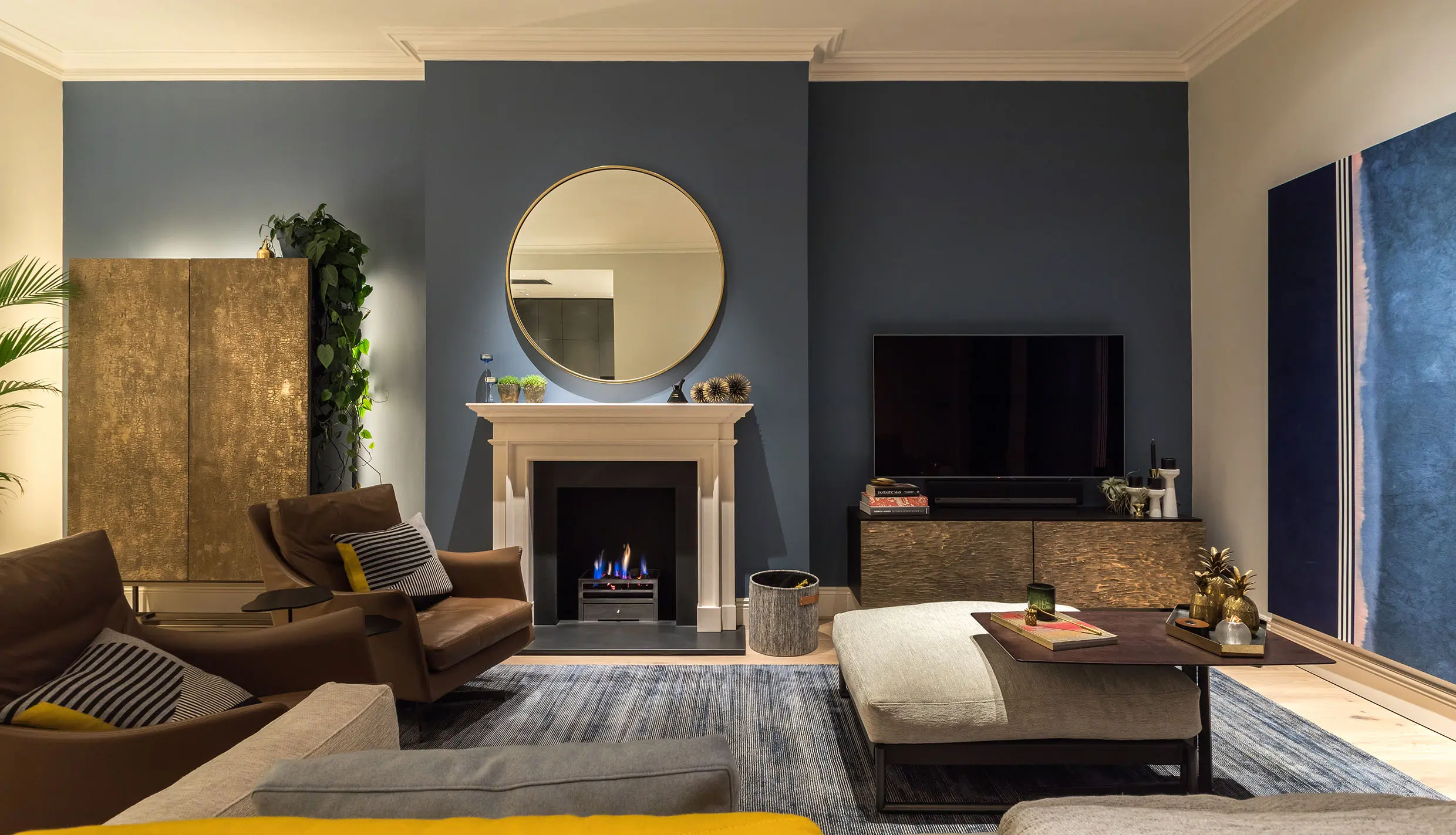 living room with deep blue walls and lit art and uplit drinks cabinet