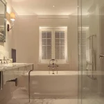 free standing bath under uplit window with marble basin