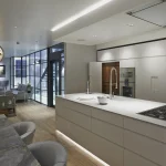 central island of kitchen with downlights over island and lighting cabinets beyond