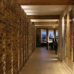 entrance down a corridor to wharf apartment with uplit brick
