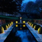 victorian water rill with lit box balls along each side and sculpture at end