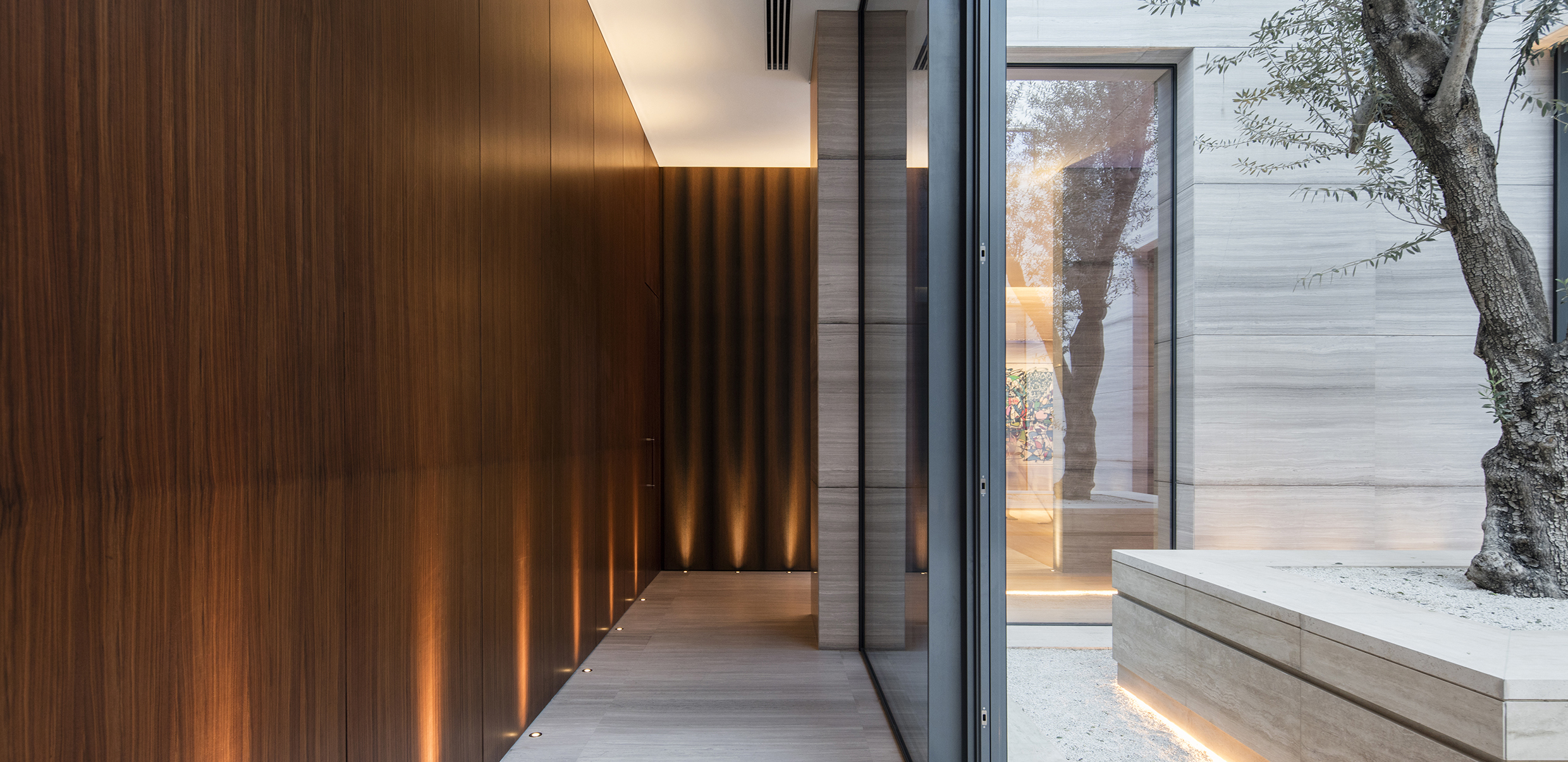 Wooden clad corridor with uplights and floating planter outside