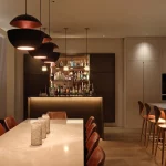 Open plan kitchen with table and kitchen island with pendants and downlight lighting