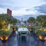 sky entertaining garden with table and uplit pots and planting