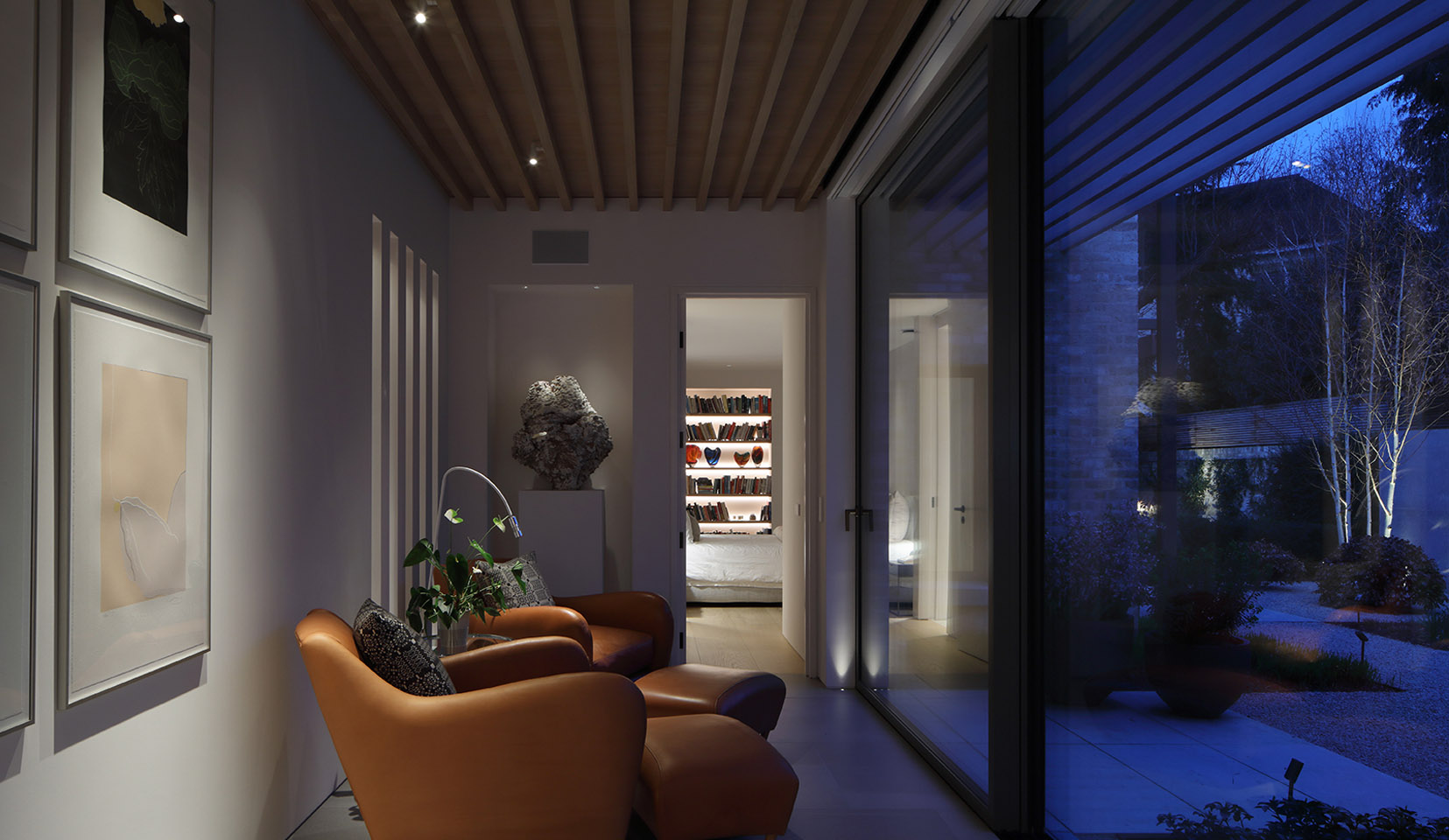 Seating area with art lit and view through doorway to lit shelving beyond